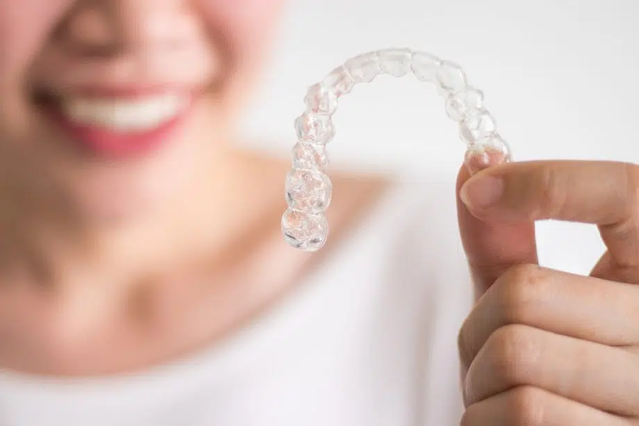 a hand holding an Invisalign clear aligner tray