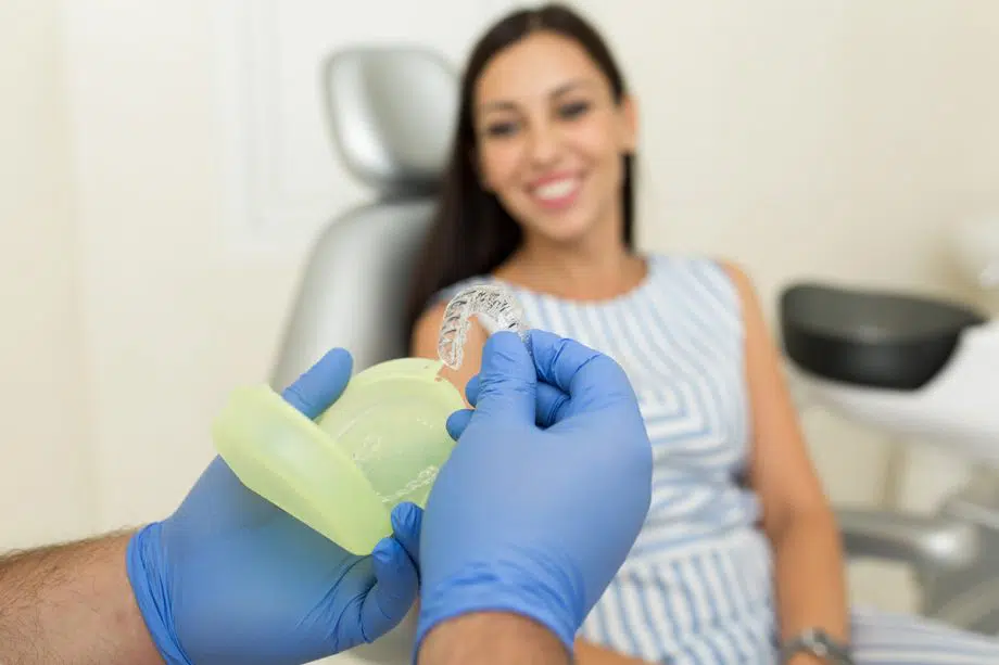 gloved hands remove Invisalign aligners from case