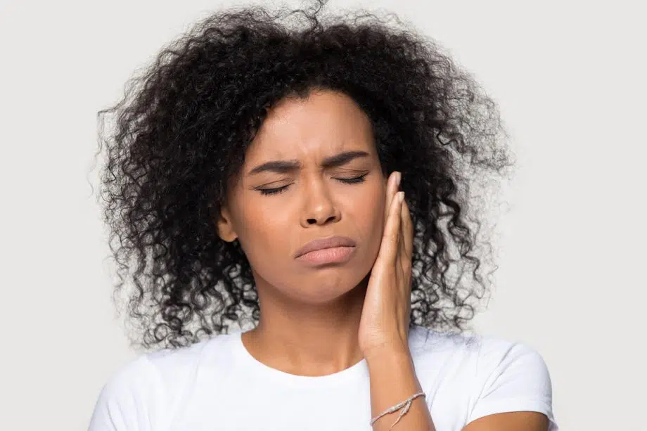 woman holding jaw and wincing in pain